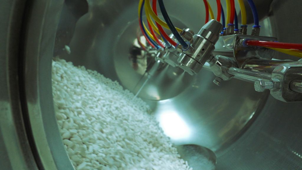 Spray nozzles coating tumbling white tablets